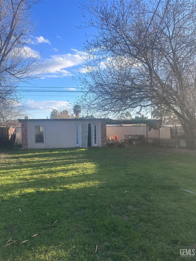 exterior space featuring a yard, fence, and stucco siding