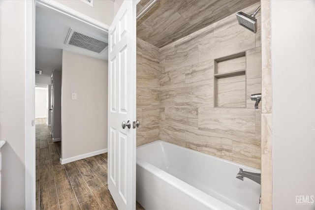 bathroom featuring wood-type flooring and tiled shower / bath