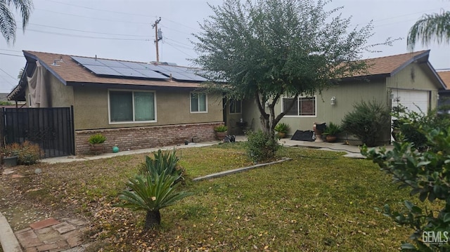 ranch-style home featuring solar panels, a garage, and a front lawn