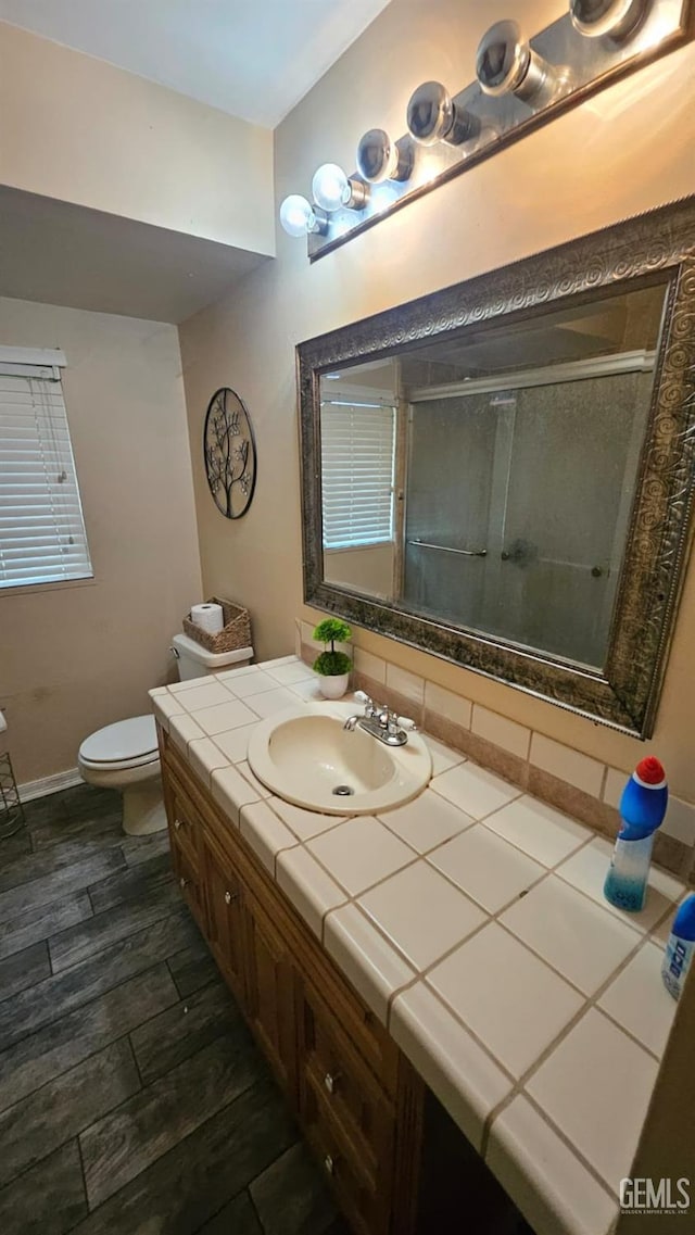 bathroom with wood-type flooring, vanity, toilet, and walk in shower