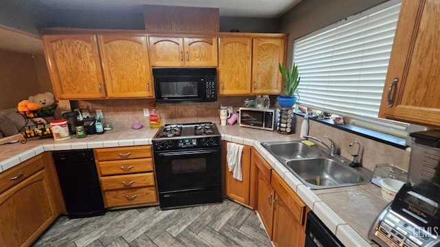 kitchen with tile counters, sink, light parquet floors, decorative backsplash, and black appliances