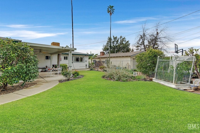 view of yard featuring a patio area, a vegetable garden, ceiling fan, and fence