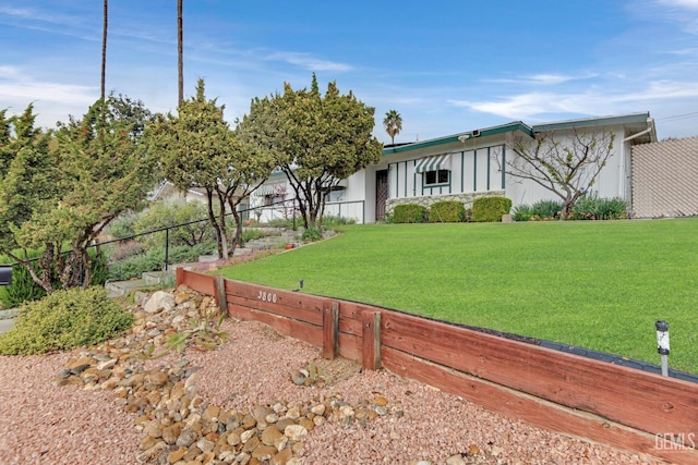 view of front of home with board and batten siding, a front yard, and fence