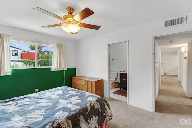 bedroom with light carpet, visible vents, connected bathroom, and ceiling fan