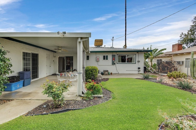 rear view of house featuring a patio, a ceiling fan, fence, stucco siding, and a lawn