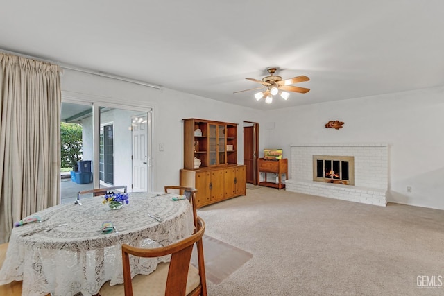 dining area with ceiling fan, a brick fireplace, and light carpet