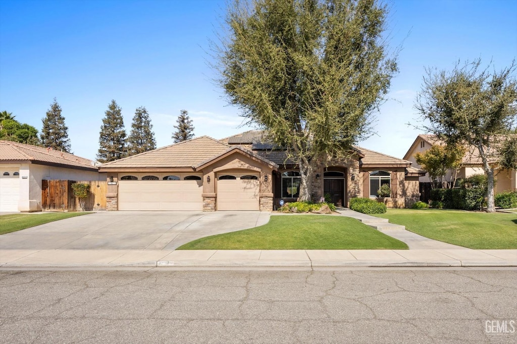 view of front of house featuring a garage, a front lawn, and solar panels