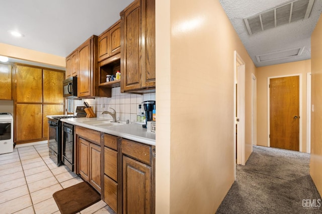 kitchen featuring a sink, brown cabinetry, visible vents, black appliances, and decorative backsplash
