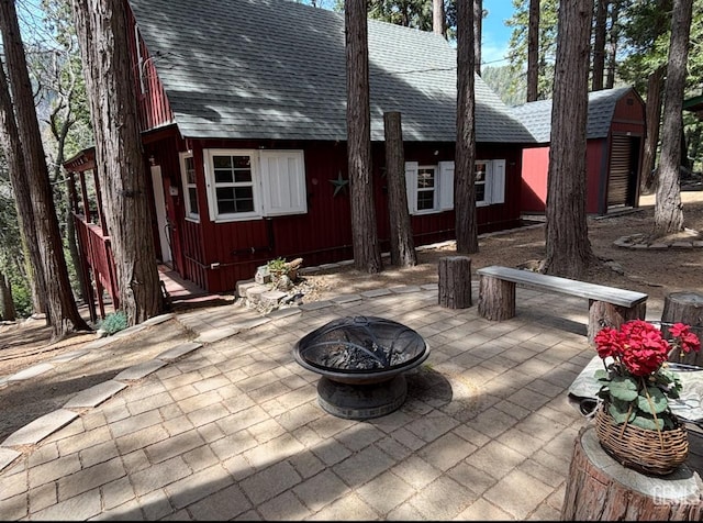 back of property with an outdoor fire pit, a patio area, and a shingled roof