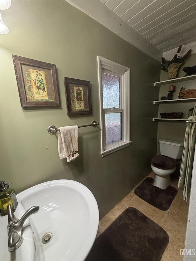 bathroom featuring toilet, tile patterned flooring, and a sink