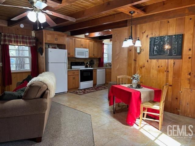 kitchen featuring wooden walls, plenty of natural light, beamed ceiling, and white appliances