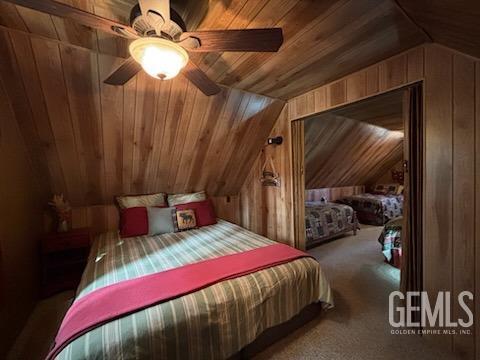 carpeted bedroom featuring wooden ceiling, ceiling fan, wooden walls, and lofted ceiling