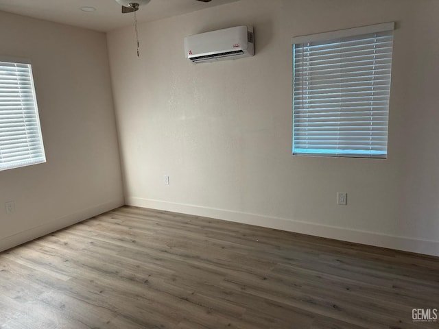 empty room featuring a wall mounted air conditioner and wood-type flooring