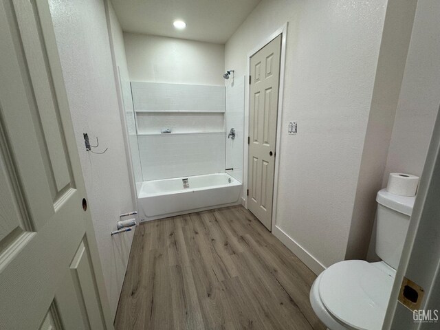 bathroom featuring bathtub / shower combination, hardwood / wood-style floors, and toilet