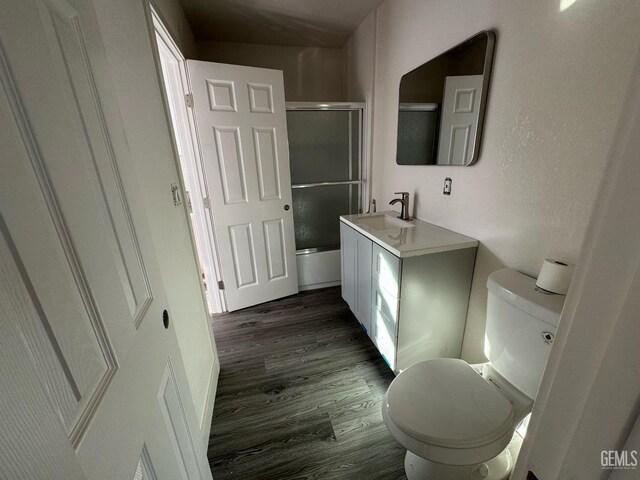 bathroom featuring hardwood / wood-style floors, vanity, a shower with shower door, and toilet