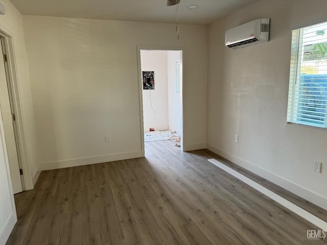 empty room with a wall mounted air conditioner, a wealth of natural light, and hardwood / wood-style flooring