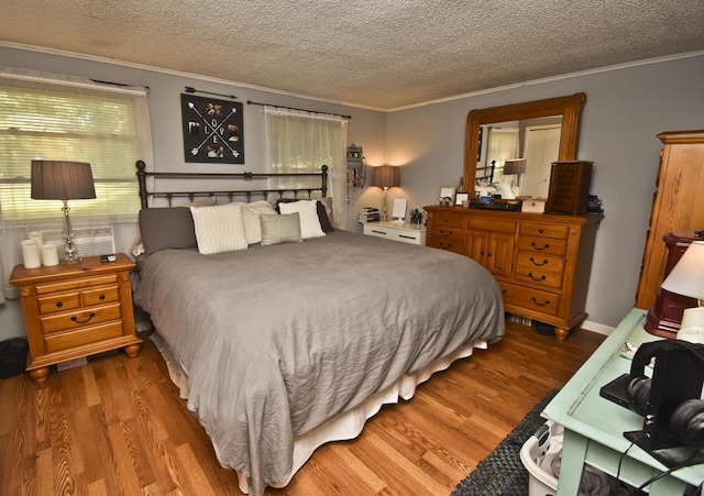 bedroom featuring a textured ceiling, wood finished floors, and crown molding