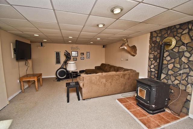 carpeted living room featuring a drop ceiling, recessed lighting, a wood stove, and baseboards