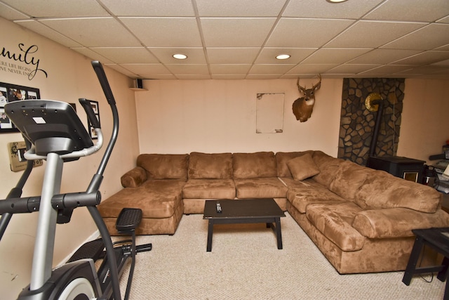 carpeted living area with a wood stove, recessed lighting, and a drop ceiling