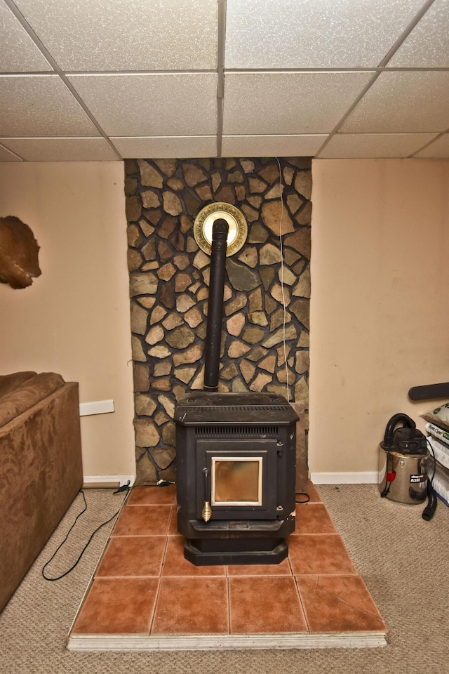 room details featuring a drop ceiling, baseboards, and a wood stove