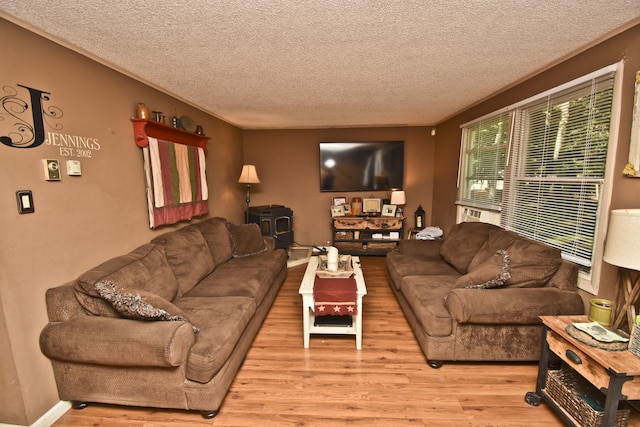 living area featuring baseboards, a textured ceiling, light wood-style flooring, and a wood stove