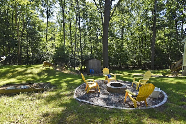 view of yard featuring a storage unit, a fire pit, and an outdoor structure