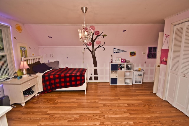 bedroom with an inviting chandelier, wood finished floors, a closet, and lofted ceiling