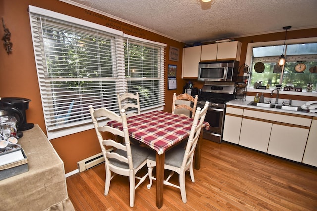 dining area featuring baseboard heating, a textured ceiling, crown molding, and light wood-style floors