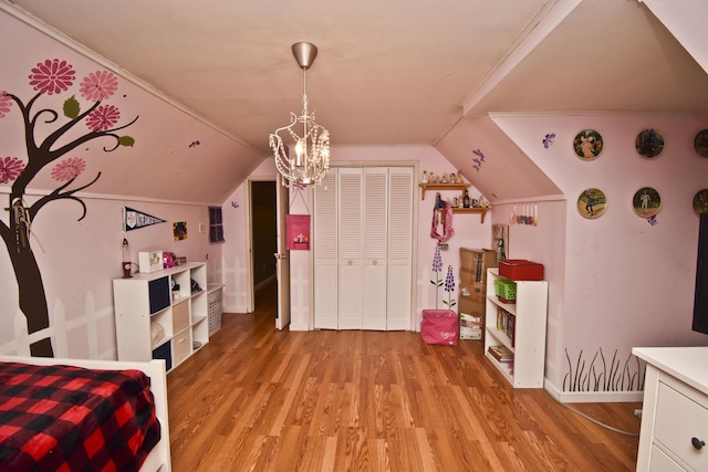 bedroom with light wood finished floors, baseboards, lofted ceiling, a closet, and a notable chandelier