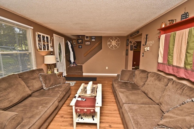 living area with baseboards, a textured ceiling, and wood finished floors