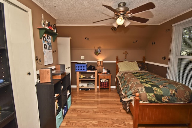 bedroom with a ceiling fan, crown molding, wood finished floors, and a textured ceiling