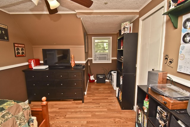 bedroom with ornamental molding, a ceiling fan, a textured ceiling, light wood finished floors, and lofted ceiling