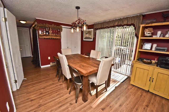 dining room with a baseboard heating unit, light wood finished floors, and a textured ceiling