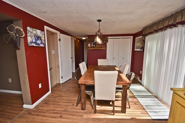 dining space featuring baseboards, a textured ceiling, and wood finished floors