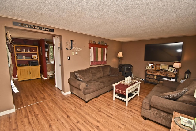 living room featuring a textured ceiling, wood finished floors, and a wood stove