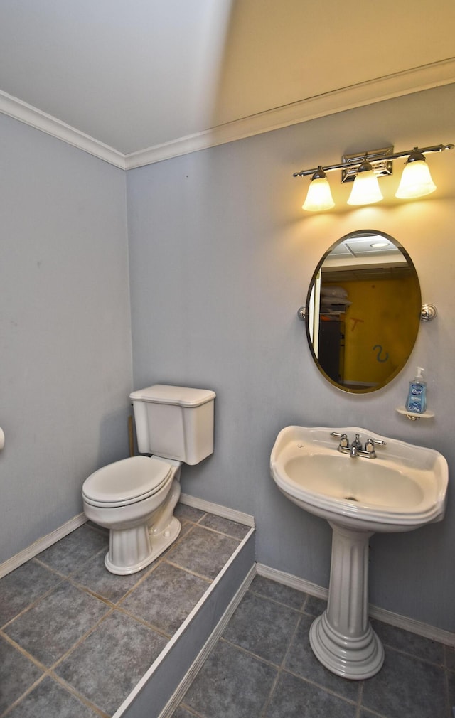 half bathroom with tile patterned floors, toilet, crown molding, and baseboards