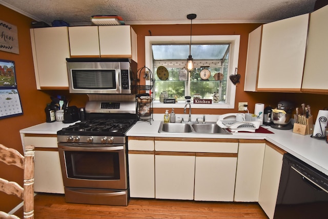 kitchen with a textured ceiling, stainless steel appliances, light countertops, and a sink