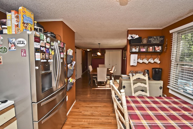 kitchen with a textured ceiling, wood finished floors, stainless steel fridge with ice dispenser, and crown molding