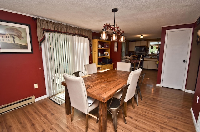 dining space with a textured ceiling, a baseboard heating unit, and wood finished floors