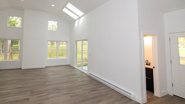 119 N Shore Dr, Albrightsville, PA 18210 - unfurnished living room featuring a baseboard heating unit, high vaulted ceiling, a skylight, plenty of natural light, and wood finished floors