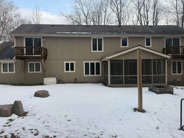 snow covered property featuring a balcony and a sunroom