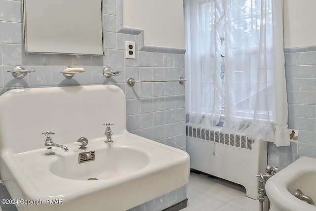 bathroom featuring a sink, tile patterned floors, tile walls, and radiator