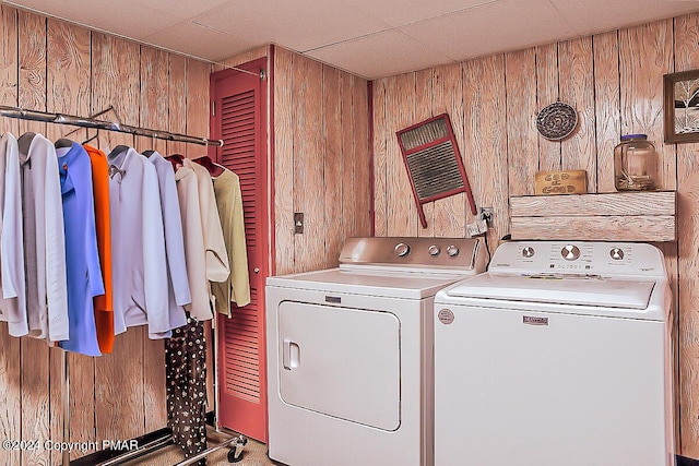 clothes washing area featuring laundry area, washing machine and clothes dryer, and wood walls