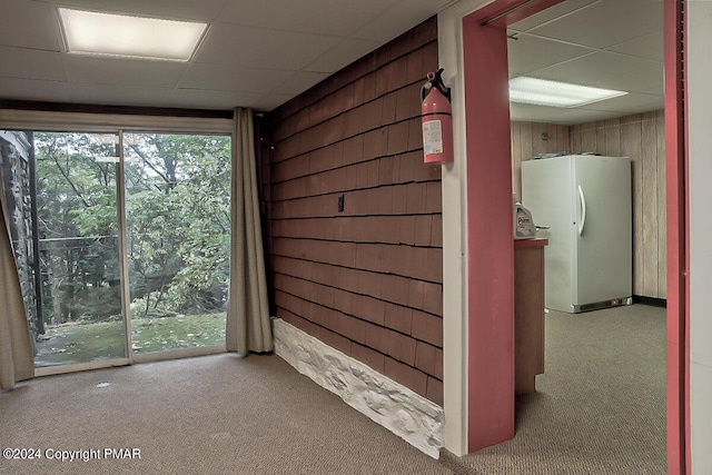 interior space featuring a paneled ceiling and wooden walls