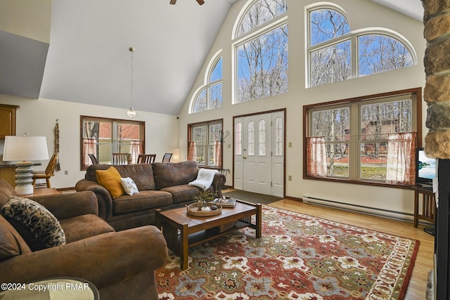 living room featuring light wood-style flooring, high vaulted ceiling, and baseboard heating