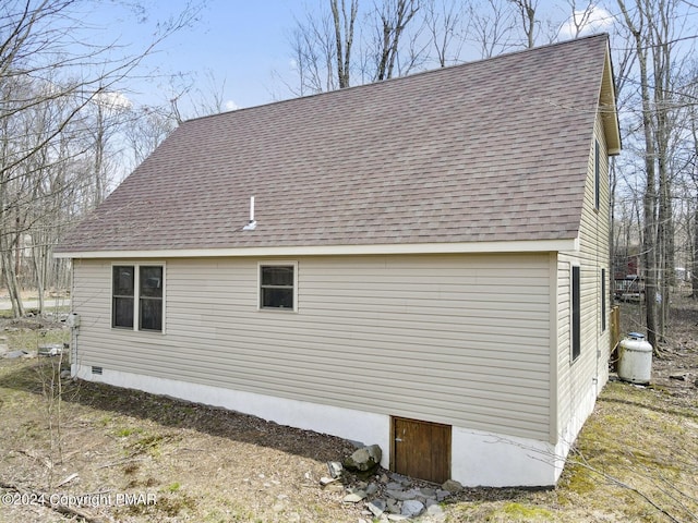 view of side of home featuring a shingled roof and crawl space