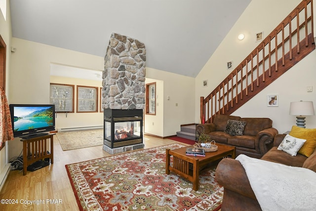 living area with lofted ceiling, stairway, wood finished floors, baseboard heating, and a fireplace