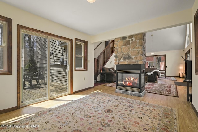 living room featuring baseboards, wood finished floors, and a stone fireplace