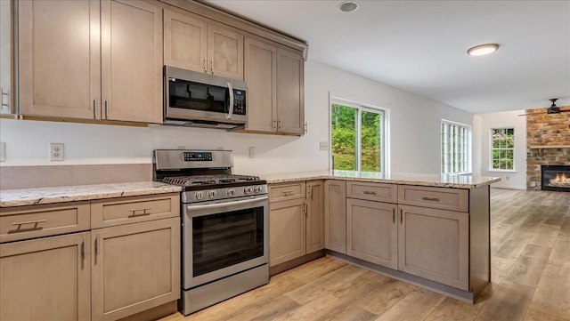 79 Delaware Dr, Jim Thorpe, PA 18229 - kitchen with appliances with stainless steel finishes, a peninsula, a stone fireplace, open floor plan, and light wood-type flooring