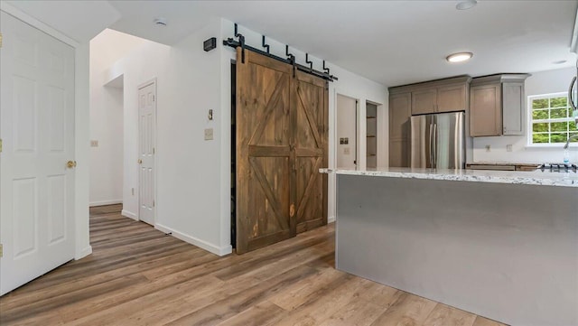 79 Delaware Dr, Jim Thorpe, PA 18229 - kitchen with freestanding refrigerator, light wood-style flooring, a barn door, light stone countertops, and baseboards